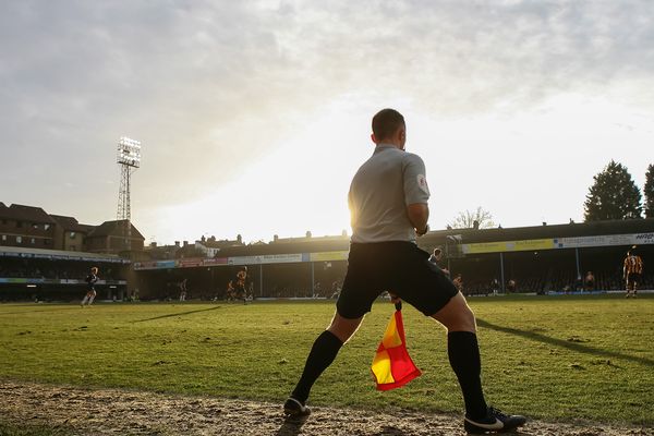 An assistant referee runs down the line as the sun sets