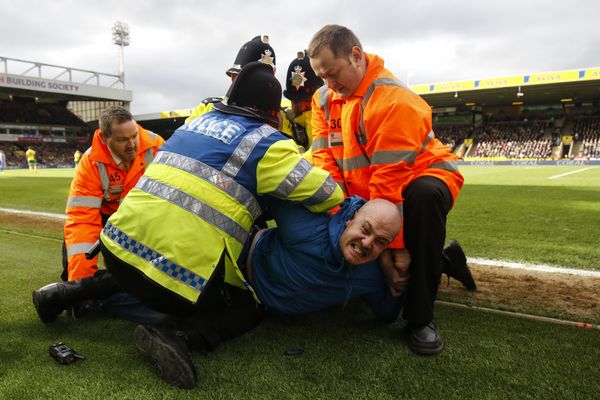 An Ipswich fan is detained for entering the pitch during the 'Old Farm Derby' against Norwich