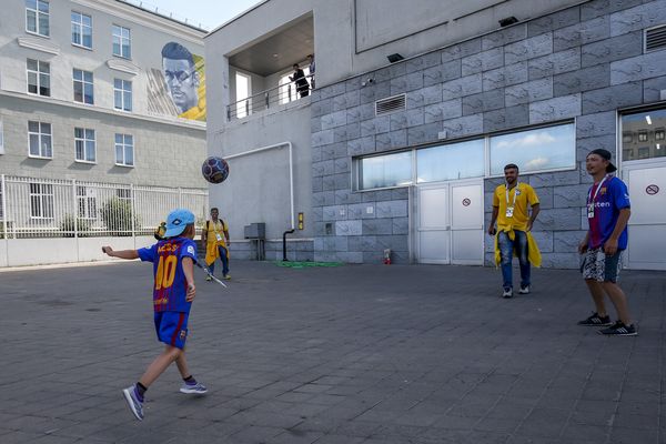 Fans play football in front of a mural of Neymar in Kazan, Russia
