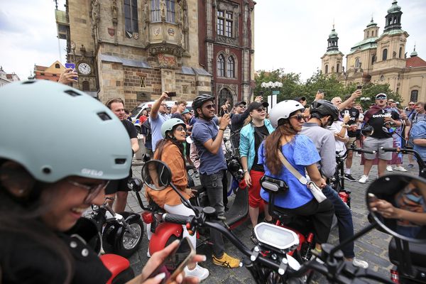 Tourists look on with bemusment as West Ham United fans drink in the centre of Prague