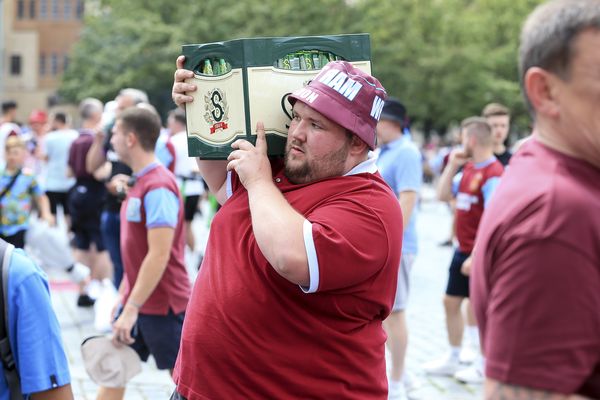 A West Ham United fan carries a crate of beer in Prague